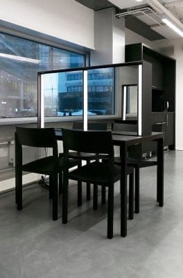 Moderniin ja minimalistiseen toimistotilaan sopii upeasti LedStore.fi:n tarjoama valaistus. Tilassa on tyylikäs musta pöytä kahdella yhteensopivalla tuolilla sekä keskellä oleva pystysuuntainen jakaja. Suuret ikkunat päästävät sisään runsaasti luonnonvaloa, jota täydentävät hillityt LED-korostukset. Oikealla näkyy pieni keittiöalue, jossa LED-valot luovat viihtyisän tunnelman.