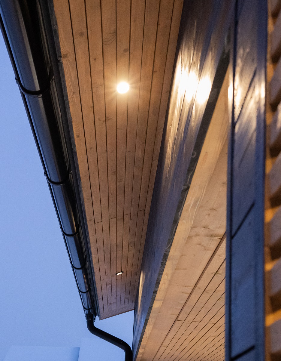 Puinen talo iltahämärässä: räystäässä loistaa LedStore.fi:n energiatehokas kattovalo sadevesikourun vieressä. - LedStore Räystäsvalaistus autokatoksessa led-spoteilla