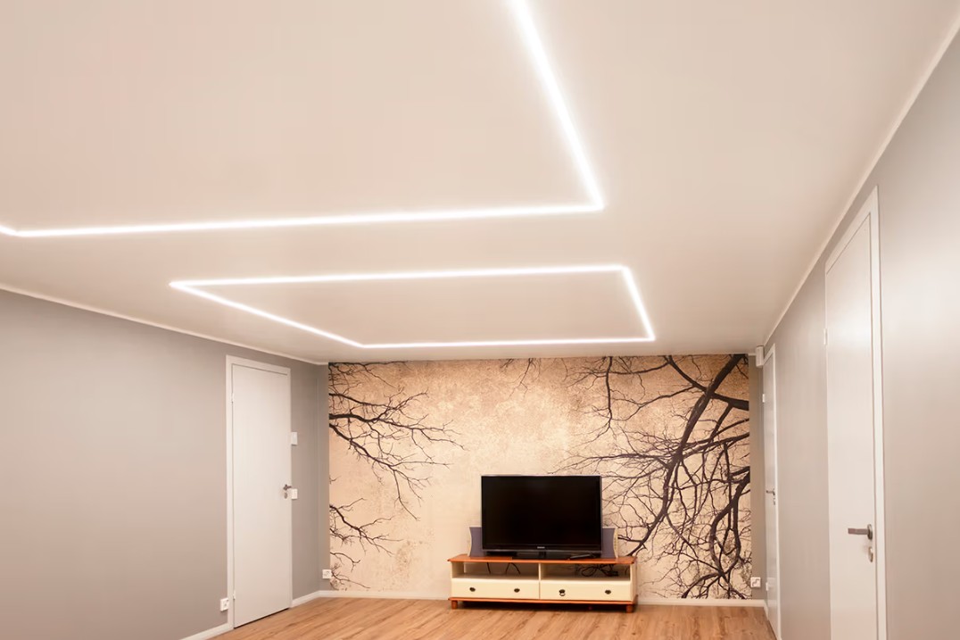 Minimalistinen olohuone, jossa on TV, tyylikäs oksatapetti sekä geometriset LED-kattovalaisimet LedStore.fi:n valikoimasta. - LedStore Minimalistinen olohuone perheen kodissa Espoon Kaitamäessä, jossa LedStore.fi:n LED-kattovalot luovat tyylikkään valaistuskokonaisuuden. Olohuoneessa on TV-taso sekä näyttävä seinämaalaus, jota korostaa laadukas LED-valaistus.